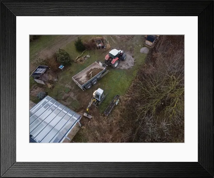 Framed Print : aerial drone shot of small, yellow excavator stands in a large garden and digs a hole for a pool in austria Framed Print : aerial drone shot of small, yellow excavator stands in a large garden and digs a hole for a pool in austria