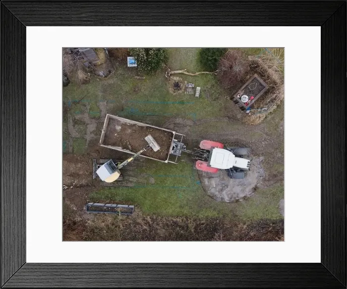 Framed Print : aerial drone shot of small, yellow excavator stands in a large garden and digs a hole for a pool in austria Framed Print : aerial drone shot of small, yellow excavator stands in a large garden and digs a hole for a pool in austria