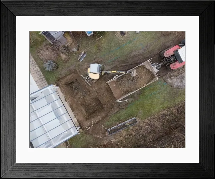 Framed Print : aerial drone shot of small, yellow excavator stands in a large garden and digs a hole for a pool in austria Framed Print : aerial drone shot of small, yellow excavator stands in a large garden and digs a hole for a pool in austria