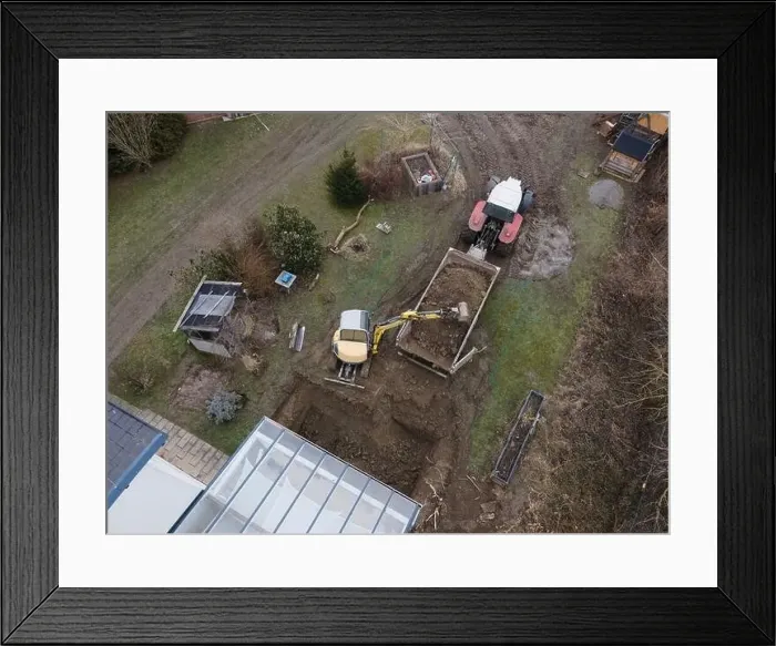 Framed Print : aerial drone shot of small, yellow excavator stands in a large garden and digs a hole for a pool in austria Framed Print : aerial drone shot of small, yellow excavator stands in a large garden and digs a hole for a pool in austria