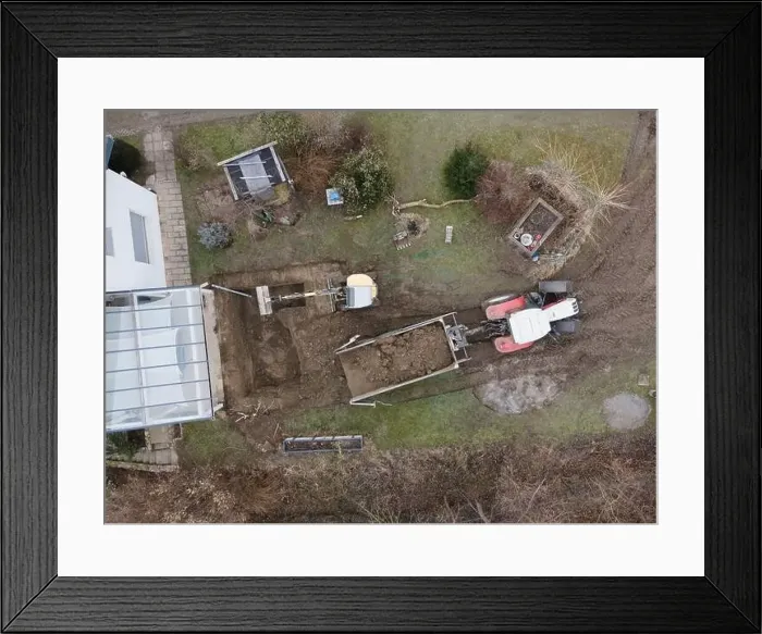 Framed Print : aerial drone shot of small, yellow excavator stands in a large garden and digs a hole for a pool in austria Framed Print : aerial drone shot of small, yellow excavator stands in a large garden and digs a hole for a pool in austria