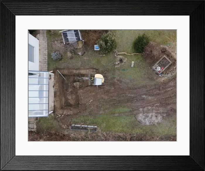 Framed Print : aerial drone shot of small, yellow excavator stands in a large garden and digs a hole for a pool in austria Framed Print : aerial drone shot of small, yellow excavator stands in a large garden and digs a hole for a pool in austria
