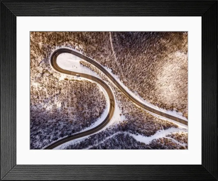 Framed Print : High angle aerial view drone image on the curved serpentine road trough the trees Framed Print : High angle aerial view drone image on the curved serpentine road trough the trees
