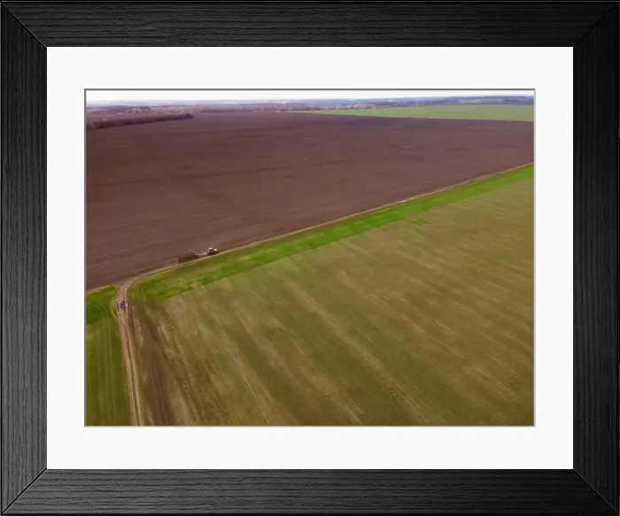 Framed Print : Aerial view of a modern yellow tractor rides across the field Framed Print : Aerial view of a modern yellow tractor rides across the field