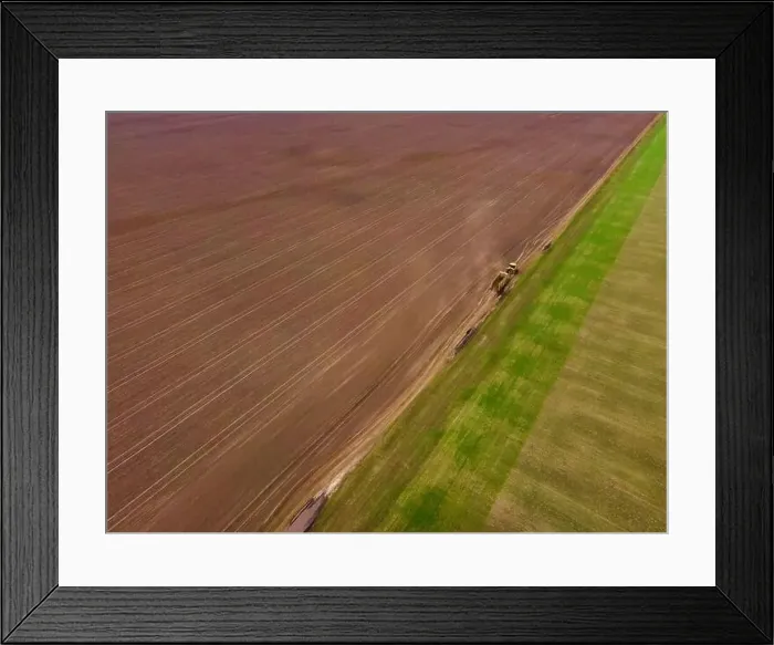 Framed Print : Aerial view of a modern yellow tractor rides across the field Framed Print : Aerial view of a modern yellow tractor rides across the field