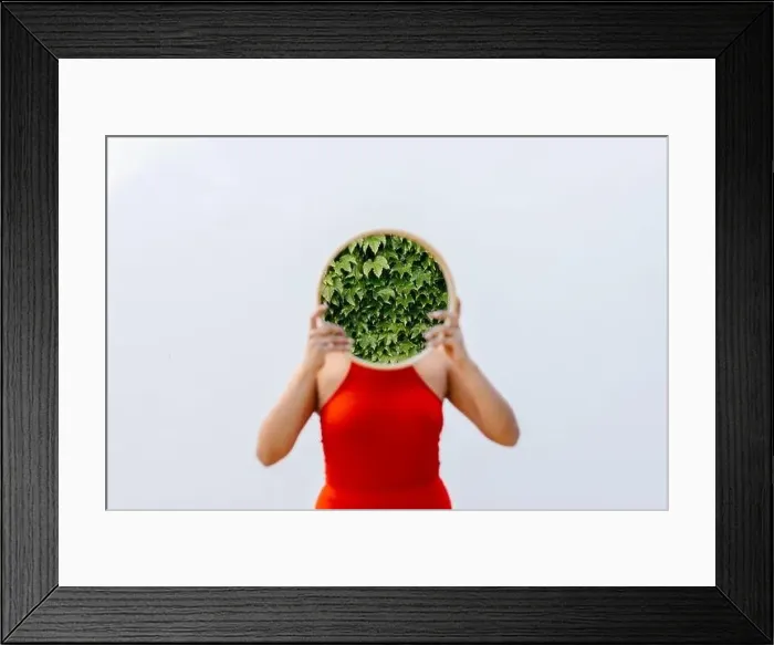 Framed Print : Woman holding mirror with reflection of plants in front of white wall Framed Print : Woman holding mirror with reflection of plants in front of white wall
