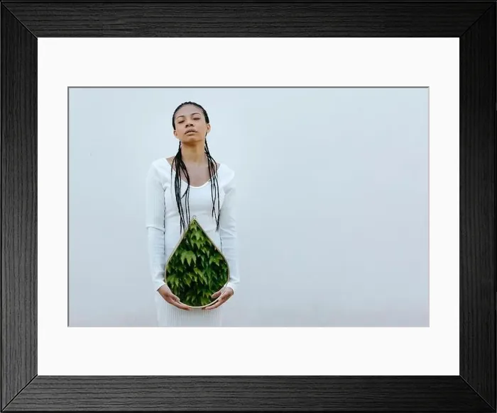 Framed Print : Serene woman holding mirror with leaves reflection in front of white wall Framed Print : Serene woman holding mirror with leaves reflection in front of white wall