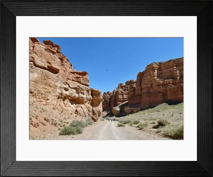 Framed Print : Tourists travel along the bottom of a deep warn colored canyon accompanied by a drone, blue sky Framed Print : Tourists travel along the bottom of a deep warn colored canyon accompanied by a drone, blue sky