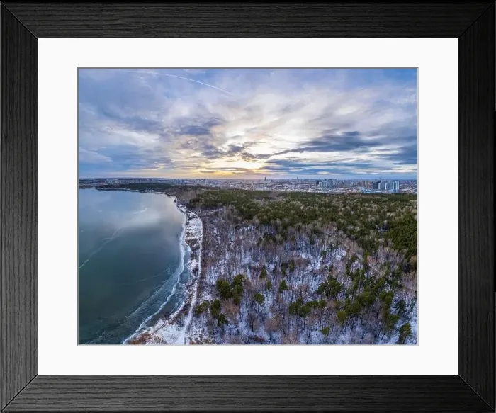 Framed Print : Snow-covered forest on lake shore with the first ice at sunset and the city on horizon Framed Print : Snow-covered forest on lake shore with the first ice at sunset and the city on horizon