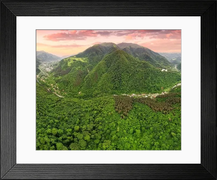 Framed Print : Drone view of a mountain valley with dense forests and a road along which houses and villages have grown