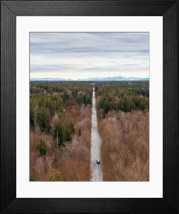 Framed Print : On the road by car driving through wide forest to the mountains in background Framed Print : On the road by car driving through wide forest to the mountains in background