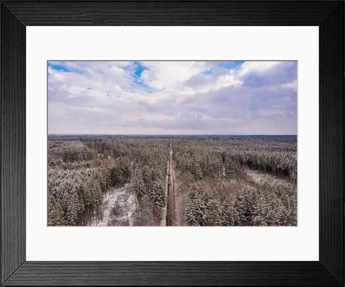 Framed Print : Idyllic winter panorama from an aerial view with a snow-covered forest and a to the horizon leading road Framed Print : Idyllic winter panorama from an aerial view with a snow-covered forest and a to the horizon leading road