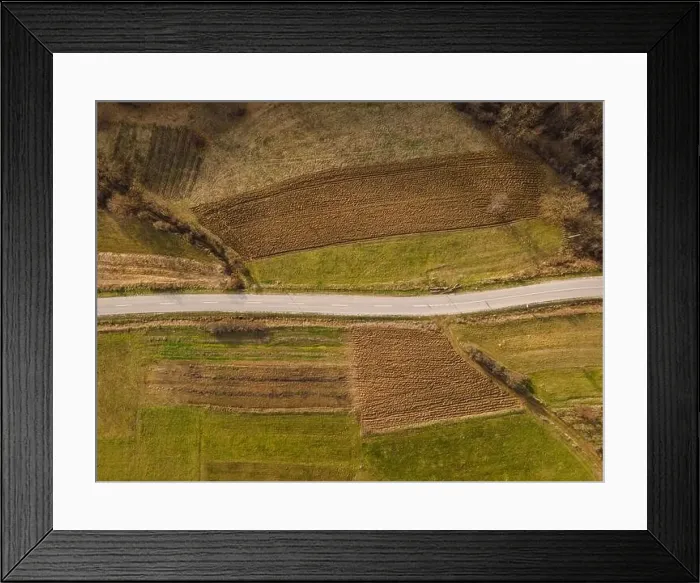 Framed Print : Aerial view top down from above on the country road in mountain range in between fields grass Framed Print : Aerial view top down from above on the country road in mountain range in between fields grass
