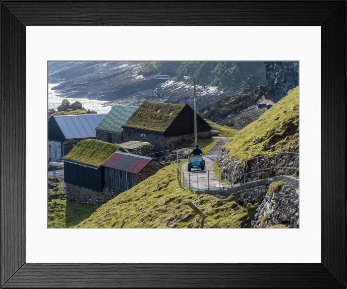 Framed Print : A farmworker takes a trailer past stonewalled farm buildings and green slopes drenched in May sunshine