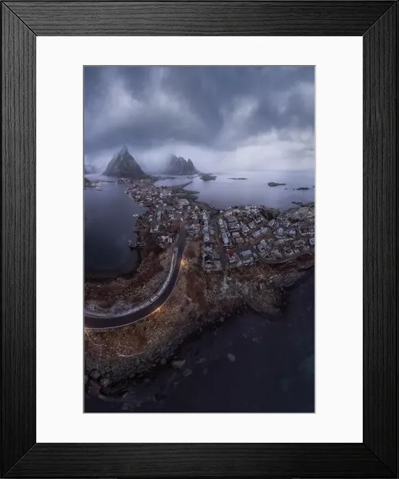 Framed Print : Aerial view of calm water of sea washing island with a village and rocky formations under cloudy sky Framed Print : Aerial view of calm water of sea washing island with a village and rocky formations under cloudy sky