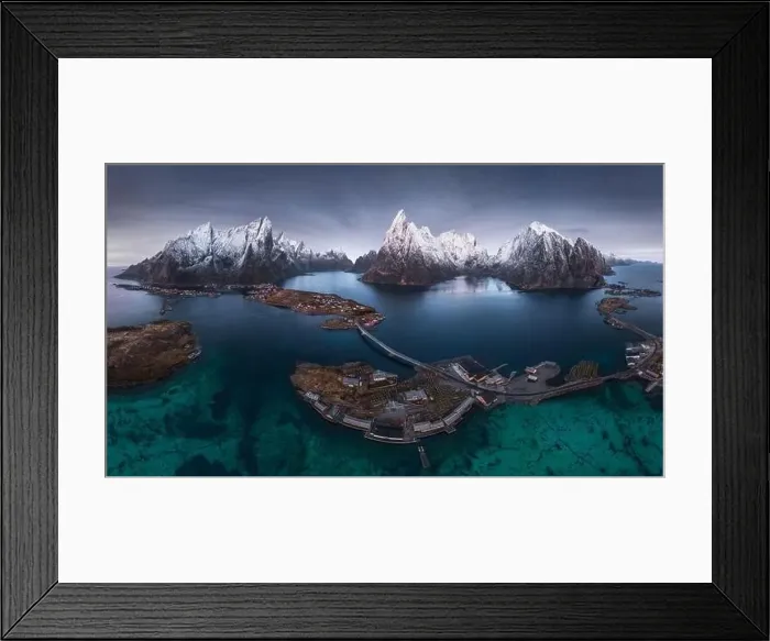 Framed Print : Aerial view of calm water of sea washing island with a village and rocky formations under cloudy sky Framed Print : Aerial view of calm water of sea washing island with a village and rocky formations under cloudy sky