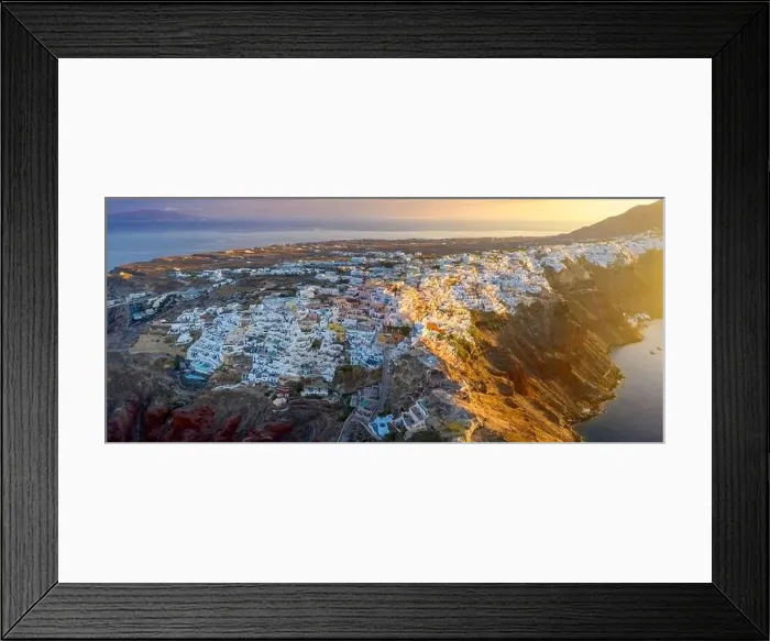 Framed Print : Picturesque Aerial drone view of famous Oia village with white houses during sunrise on Santorini island Framed Print : Picturesque Aerial drone view of famous Oia village with white houses during sunrise on Santorini island