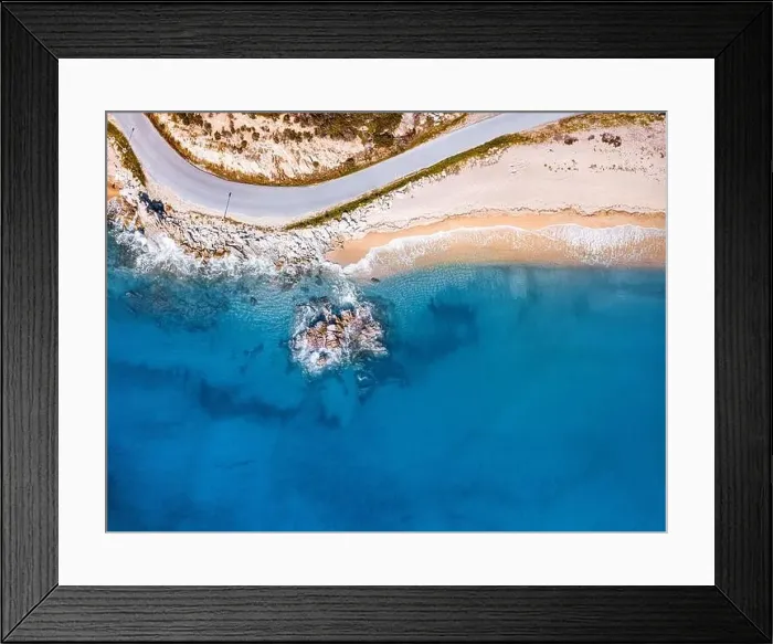 Framed Print : Aerial view of an idyllic sea sandy beach with asphalt winding road and rocky cliff. Background for travel and vacation