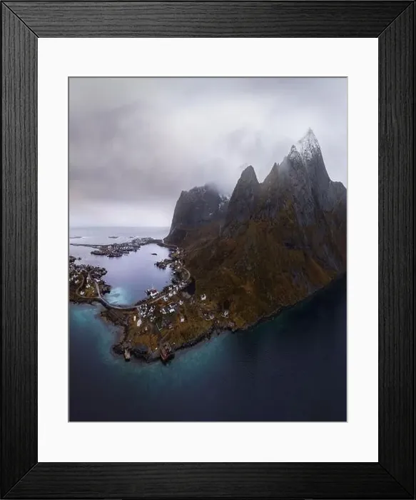 Framed Print : Aerial view of calm water of sea washing island with rocky formations under cloudy sky with small village in Rein Framed Print : Aerial view of calm water of sea washing island with rocky formations under cloudy sky with small village in Rein