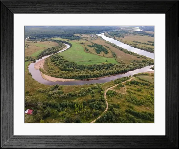 Framed Print : River between wavy road and lawns with trees in countryside Framed Print : River between wavy road and lawns with trees in countryside