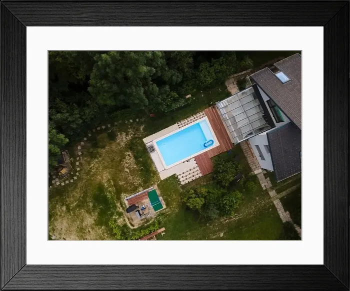 Framed Print : Drone flight over beautiful green garden with pool and the wooden terrace of the pool is currently in progress