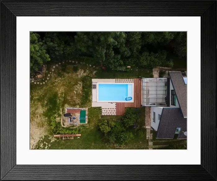 Framed Print : Drone flight over beautiful green garden with pool and the wooden terrace of the pool is currently in progress Framed Print : Drone flight over beautiful green garden with pool and the wooden terrace of the pool is currently in progress