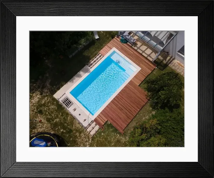 Framed Print : aerial drone flight over beautiful green garden with pool and the wooden deck of the pool is in progress