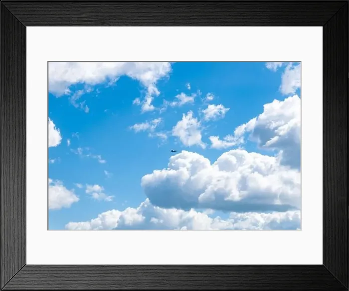 Framed Print : in a blue sky with beautiful clouds flies an airplane Framed Print : in a blue sky with beautiful clouds flies an airplane