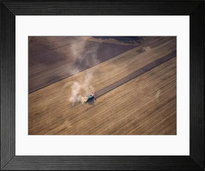 Framed Print : Agricultural machines harvest wheat in the field. Aerial shot from above. There is a lot of dust around the harvester Framed Print : Agricultural machines harvest wheat in the field. Aerial shot from above. There is a lot of dust around the harvester