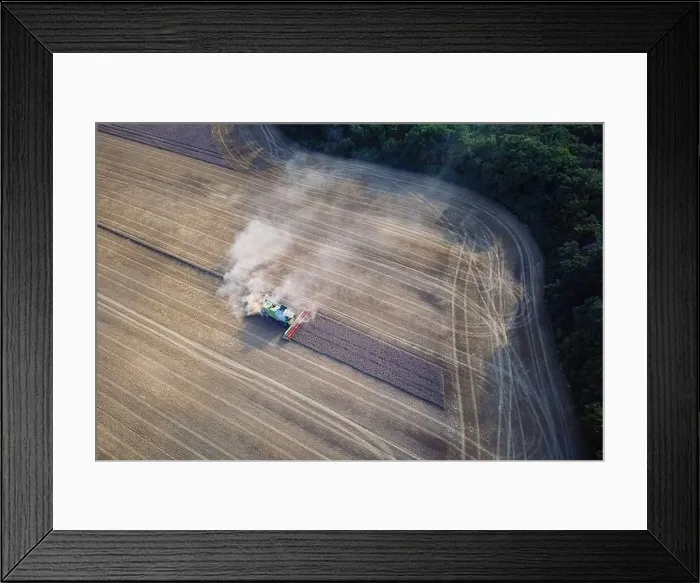 Framed Print : Agricultural machines harvest wheat in the field. Aerial shot from above. There is a lot of dust around the harvester Framed Print : Agricultural machines harvest wheat in the field. Aerial shot from above. There is a lot of dust around the harvester