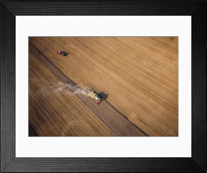 Framed Print : Agricultural machines harvest wheat in the field. Aerial shot from above. There is a lot of dust around the harvester Framed Print : Agricultural machines harvest wheat in the field. Aerial shot from above. There is a lot of dust around the harvester
