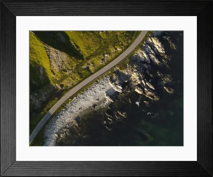 Framed Print : Top down view of a road on a sea shore. Cliffs covered with greenery, rocky shore and a dark blue sea Framed Print : Top down view of a road on a sea shore. Cliffs covered with greenery, rocky shore and a dark blue sea