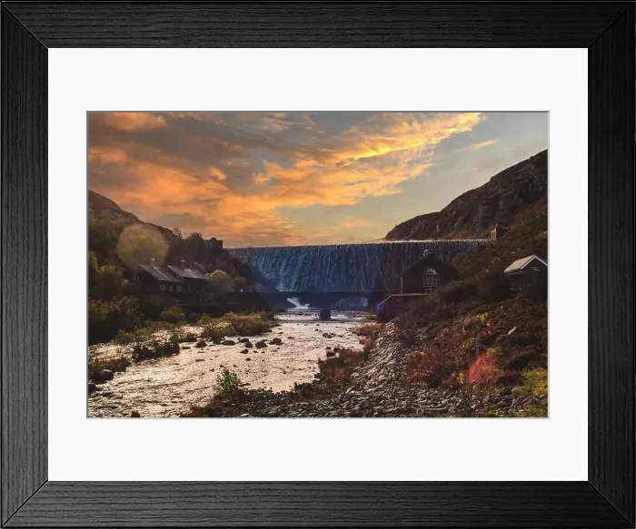 Framed Print : Water flowing over Caban Coch dam in mid Wales with the sun setting behind it