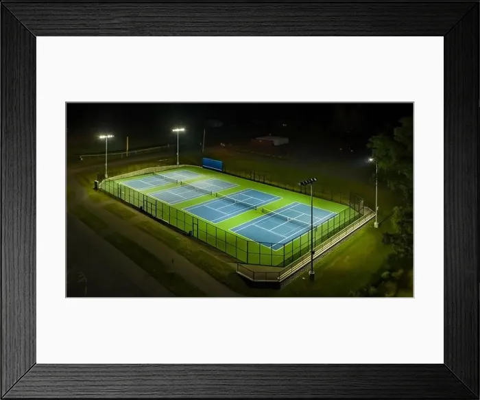 Framed Print : Evening aerial photo of outdoor blue tennis courts with pickleball lines with lights turned on Framed Print : Evening aerial photo of outdoor blue tennis courts with pickleball lines with lights turned on