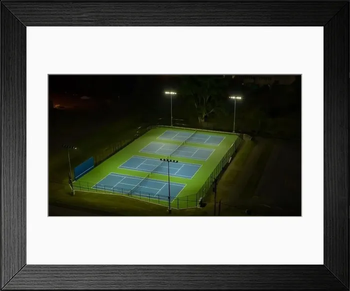 Framed Print : Evening aerial video of outdoor blue tennis courts with pickleball lines with lights turned on Framed Print : Evening aerial video of outdoor blue tennis courts with pickleball lines with lights turned on