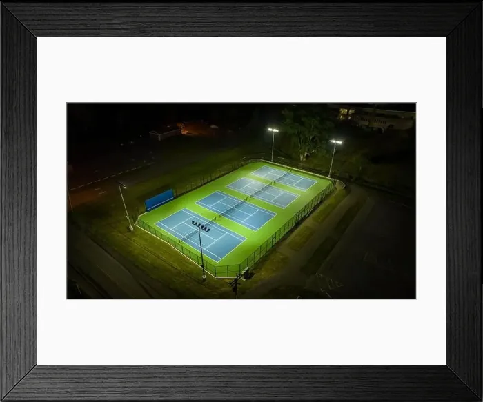 Framed Print : Evening aerial video of outdoor blue tennis courts with pickleball lines with lights turned on Framed Print : Evening aerial video of outdoor blue tennis courts with pickleball lines with lights turned on