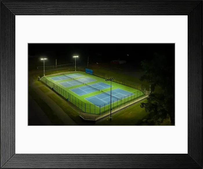 Framed Print : Evening aerial video of outdoor blue tennis courts with pickleball lines with lights turned on Framed Print : Evening aerial video of outdoor blue tennis courts with pickleball lines with lights turned on