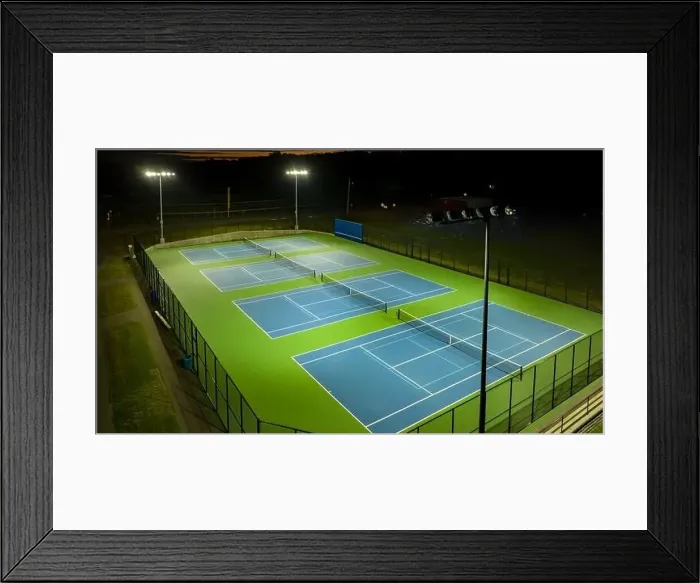 Framed Print : Evening aerial video of outdoor blue tennis courts with pickleball lines with lights turned on Framed Print : Evening aerial video of outdoor blue tennis courts with pickleball lines with lights turned on