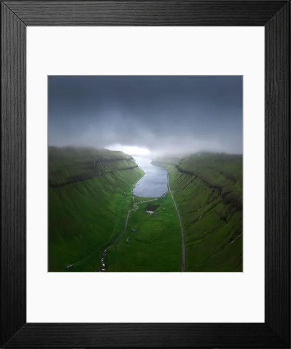 Framed Print : Drone view of curvy roads going on green mossy fjord near calm sea water against gray overcast sky on stormy day Framed Print : Drone view of curvy roads going on green mossy fjord near calm sea water against gray overcast sky on stormy day