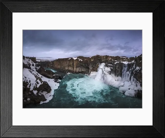 Framed Print : Picturesque drone view of Aldeyjarfoss waterfall falling from rough snowy cliff against cloudy evening sky in winter in