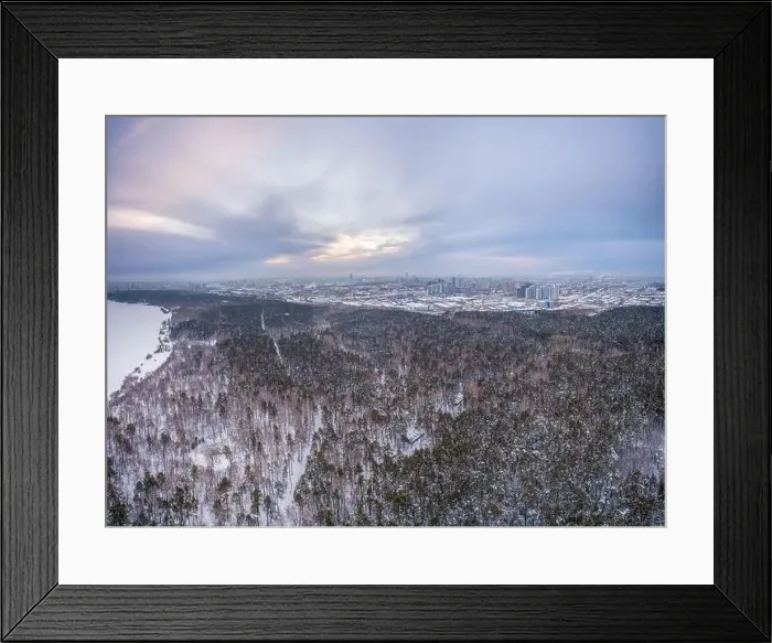 Framed Print : Snow-covered forest on lake shore with ice at sunset and the city on horizon Framed Print : Snow-covered forest on lake shore with ice at sunset and the city on horizon