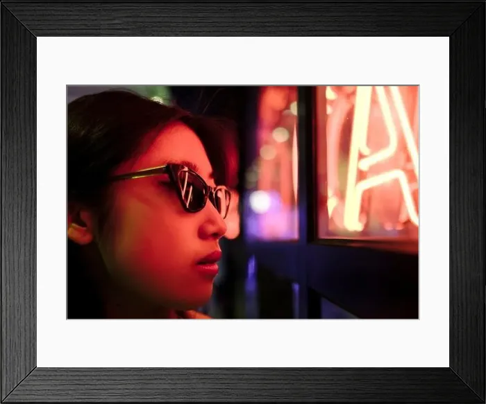 Framed Print : Young woman wearing sunglasses by illuminated wall with neon lights