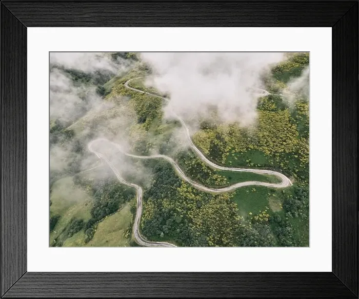 Framed Print : image taken with a drone of a long road with many curves on the slope of the green mountain between grassy vegetation Framed Print : image taken with a drone of a long road with many curves on the slope of the green mountain between grassy vegetation