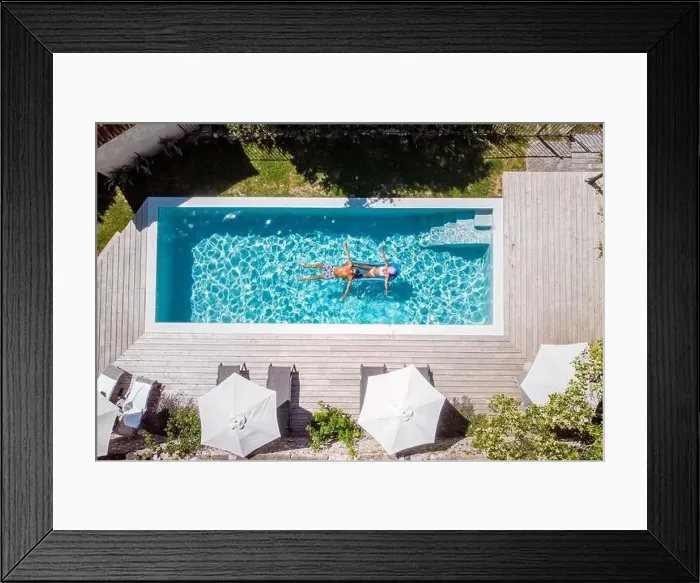 Framed Print : two people swim in the pool at the hotel