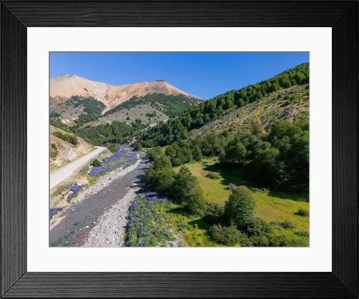 Framed Print : Aerial view of the Carretera Austral with a crystal clear creek along the road and forested hills Framed Print : Aerial view of the Carretera Austral with a crystal clear creek along the road and forested hills