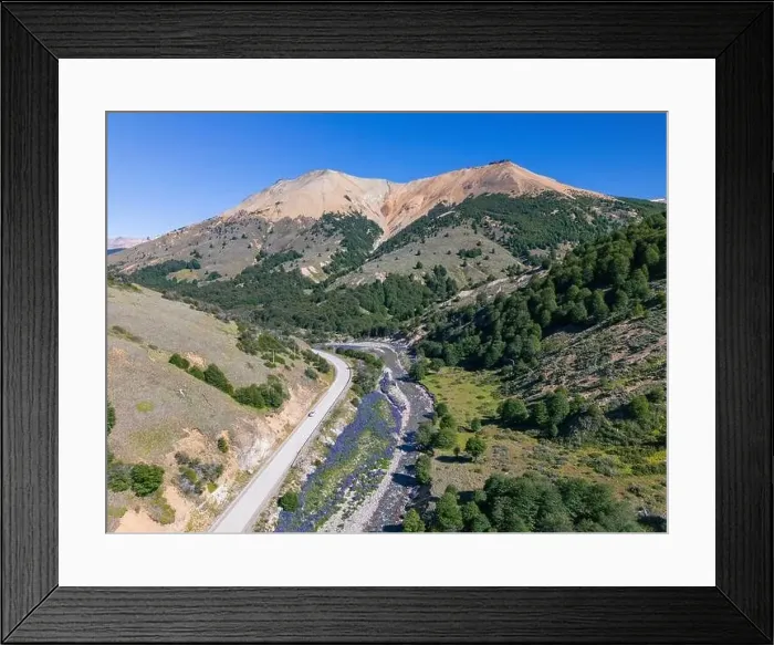 Framed Print : Aerial view of the Carretera Austral with a crystal clear creek along the road and forested hills Framed Print : Aerial view of the Carretera Austral with a crystal clear creek along the road and forested hills
