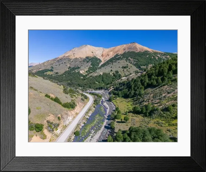 Framed Print : Aerial view of the Carretera Austral with a crystal clear creek along the road and forested hills Framed Print : Aerial view of the Carretera Austral with a crystal clear creek along the road and forested hills