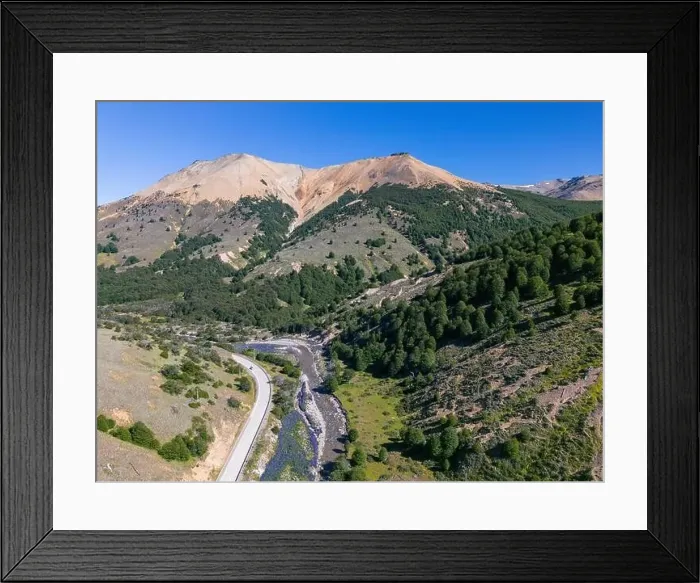 Framed Print : Aerial view of the Carretera Austral with a crystal clear creek along the road and forested hills Framed Print : Aerial view of the Carretera Austral with a crystal clear creek along the road and forested hills