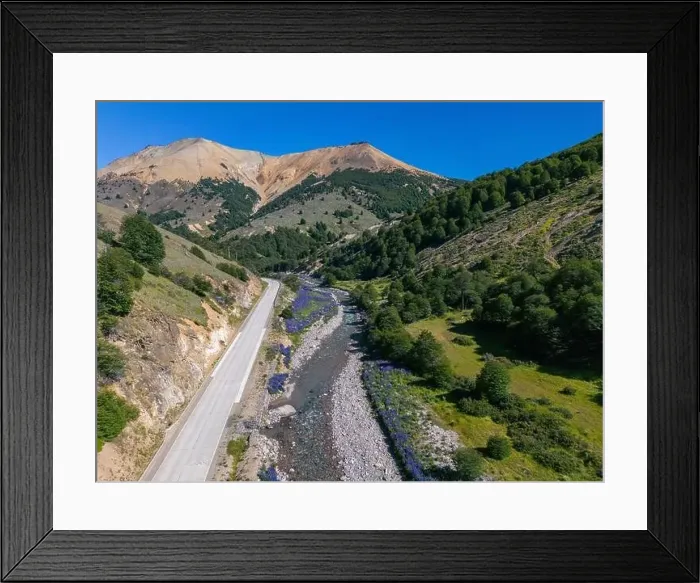 Framed Print : Aerial view of the Carretera Austral with a crystal clear creek along the road and forested hills Framed Print : Aerial view of the Carretera Austral with a crystal clear creek along the road and forested hills
