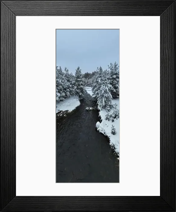 Framed Print : An aerial view of a frozen river flowing through snow-covered forests on a cloudy sunset sky background Framed Print : An aerial view of a frozen river flowing through snow-covered forests on a cloudy sunset sky background